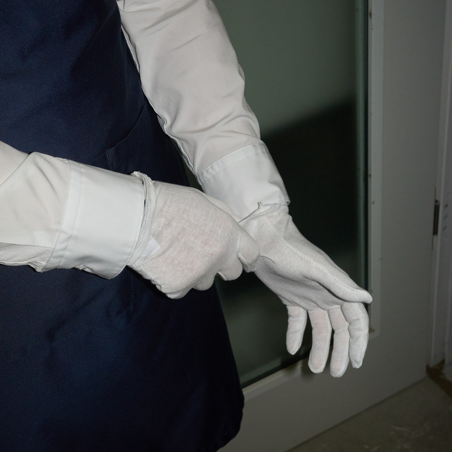 Mitarbeiterin von Ketterer Kunst zieht weiße Handschuhe an, bevor sie ein Werk in die Hand nimmt