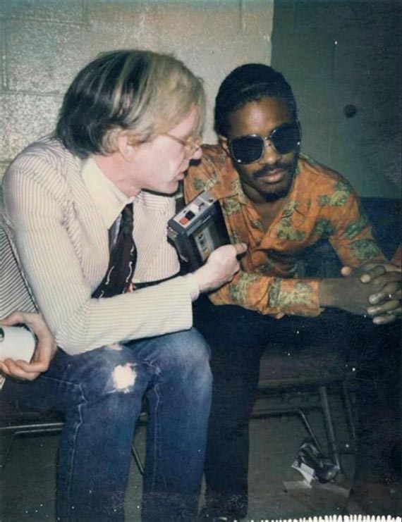 Abbildung zu: Stevie Wonder und Andy Warhol backstage bei einem Rolling-Stones-Konzert im Madison Square Garden 1972. © The Andy Warhol Foundation for the Visual Arts