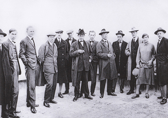 Abbildung zu: Die Bauhaus Meister auf dem Dach des Bauhausgeländes in Dessau, Dez. 1926, von r. nach l.: Oskar Schlemmer, Gunta Stölzl, Lyonel Feininger, Paul Klee, Wassily Kandinsky, Marcel Breuer, Walter Gropius und weitere, Foto: unbekannt.